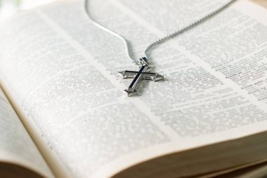 Metal haç tespihi, açık sayfa kitabına yerleştirilmiş. Yumuşak odak, İncil 'de din bilginlerinin incelenmesi konsepti..