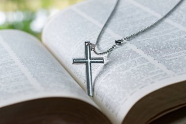 Metal haç tespihi, açık sayfa kitabına yerleştirilmiş. Yumuşak odak, İncil 'de din bilginlerinin incelenmesi konsepti..