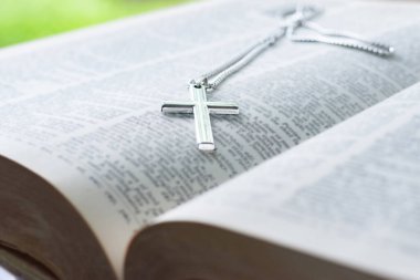 Metal haç tespihi, açık sayfa kitabına yerleştirilmiş. Yumuşak odak, İncil 'de din bilginlerinin incelenmesi konsepti..