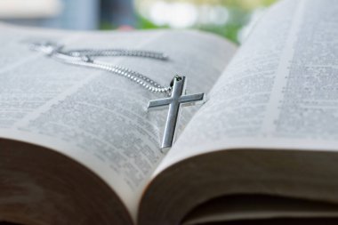 Metal haç tespihi, açık sayfa kitabına yerleştirilmiş. Yumuşak odak, İncil 'de din bilginlerinin incelenmesi konsepti..