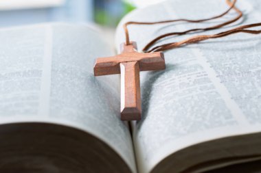 Açılmış sayfa kitabına tahta haç, yumuşak odak, Hıristiyanlık rahiplerinin İncil çalışması konsepti..