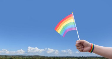 Gökkuşağı bayrakları açık bluesky, kopyalama alanı, insanları cinsiyet çeşitliliğini desteklemeye ve desteklemeye çağırma ve gurur ayında lgbtq + 'yı kutlamaya çağırma kavramına karşı el ele gösteriyor.