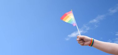 Gökkuşağı bayrakları açık bluesky, kopyalama alanı, insanları cinsiyet çeşitliliğini desteklemeye ve desteklemeye çağırma ve gurur ayında lgbtq + 'yı kutlamaya çağırma kavramına karşı el ele gösteriyor.