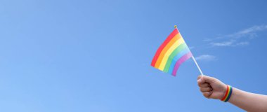 Gökkuşağı bayrakları açık bluesky, kopyalama alanı, insanları cinsiyet çeşitliliğini desteklemeye ve desteklemeye çağırma ve gurur ayında lgbtq + 'yı kutlamaya çağırma kavramına karşı el ele gösteriyor.