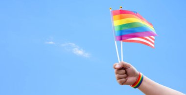 Gökkuşağı bayrakları ve Amerikan bayrağı açık mavi maviye, kopyalama alanına, insanları cinsiyet çeşitliliğini desteklemeye ve yüceltmeye çağırma ve gurur ayında lgbtq + 'yı kutlamaya çağırma konseptine el sallıyor..
