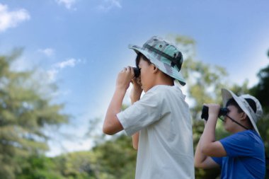 Dürbün, açık havada öğrenme, merak ve çocukluk macerasını yeşil, orman benzeri bir ortamda kullanarak doğayı keşfeden iki Asyalı çocuk..