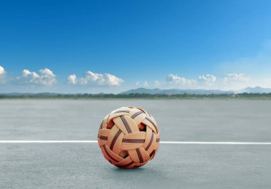 Sepak, açık hava sahasının kum zemininde topu, bulanık mavi gökyüzü ve manzara arka planı, Güneydoğu Asya ülkelerindeki eğlence aktivitesi ve açık hava sporları konsepti.