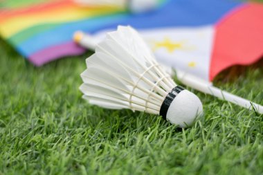 Beyaz krema servisi, badminton spor ekipmanları, Filipinler bayrağı ve gökkuşağı bayrağının önündeki yeşil çimlere yerleştirilmiş yerler, tüm cinsiyetler ve lgbtq + insanlar için badminton sporu kavramı.