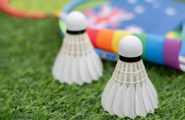 Beyaz Krem Mekik, badminton spor ekipmanları, Avustralya ulusal bayrağı ve gökkuşağı bayrağının önündeki yeşil çimlere yerleştirilmiş yerler, tüm cinsiyetler ve lgbtq + insanları için badminton sporu kavramı.