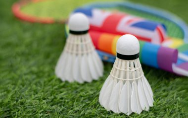 Beyaz Krem Mekik, badminton spor ekipmanları, İngiliz ulusal bayrağı ve gökkuşağı bayrağının önündeki yeşil çimlere yerleştirilmiş yerler, tüm cinsiyetler ve lgbtq + insanları için badminton sporu kavramı.