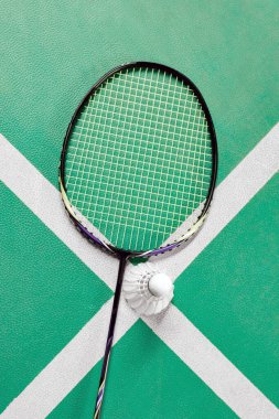 Badminton spor ekipmanları, raketler ve mekiklerin horozları, kapalı sahada badminton zemininde, yumuşak odaklanma.