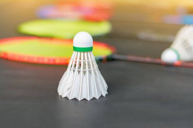 Badminton spor ekipmanları, raketler ve mekiklerin horozları, kapalı sahada badminton zemininde, yumuşak odaklanma.