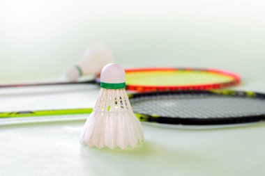 Badminton spor ekipmanları, raketler ve mekiklerin horozları, kapalı sahada badminton zemininde, yumuşak odaklanma.