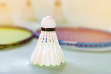 Badminton spor ekipmanları, raketler ve mekiklerin horozları, kapalı sahada badminton zemininde, yumuşak odaklanma.