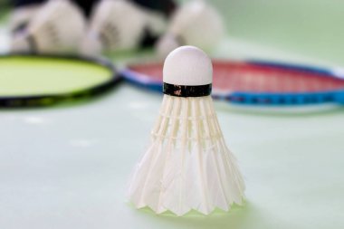 Badminton spor ekipmanları, raketler ve mekiklerin horozları, kapalı sahada badminton zemininde, yumuşak odaklanma.