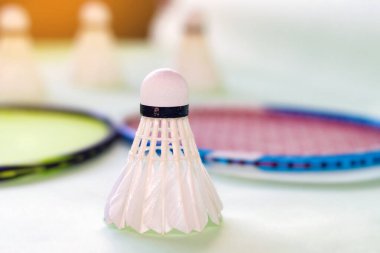Badminton spor ekipmanları, raketler ve mekiklerin horozları, kapalı sahada badminton zemininde, yumuşak odaklanma.