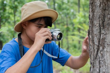 Çocuk parktaki ağaçta dürbünden bakıyor..