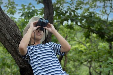 Çocuk parktaki ağaçta dürbünden bakıyor..