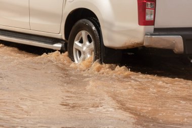 Şiddetli yağışlı bir mevsim nedeniyle çamurlu yağmurlar bölgeyi birbirine bağlayan ana yolları sular altında bıraktı, arabaların geçmesini zorlaştırdı ve motor arızalarına yol açtı, hareket halinde, araba sigortası konsepti, hareket halinde.