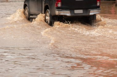 Şiddetli yağışlı bir mevsim nedeniyle çamurlu yağmurlar bölgeyi birbirine bağlayan ana yolları sular altında bıraktı, arabaların geçmesini zorlaştırdı ve motor arızalarına yol açtı, hareket halinde, araba sigortası konsepti, hareket halinde.