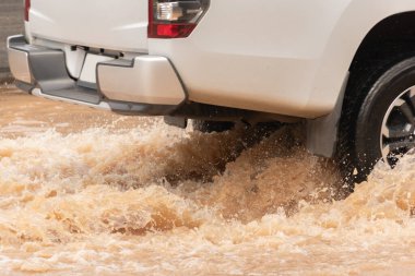 Şiddetli yağışlı bir mevsim nedeniyle çamurlu yağmurlar bölgeyi birbirine bağlayan ana yolları sular altında bıraktı, arabaların geçmesini zorlaştırdı ve motor arızalarına yol açtı, hareket halinde, araba sigortası konsepti, hareket halinde.