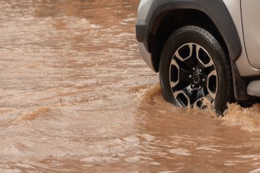 Şiddetli yağışlı bir mevsim nedeniyle çamurlu yağmurlar bölgeyi birbirine bağlayan ana yolları sular altında bıraktı, arabaların geçmesini zorlaştırdı ve motor arızalarına yol açtı, hareket halinde, araba sigortası konsepti, hareket halinde.