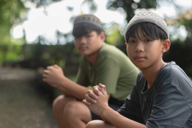 Dini ya da kültürel şapkalar takan iki genç Asyalı dışarıda dinleniyor, sakin, düşünceli bir arkadaşlık ve yansıma anı yaşıyorlar..