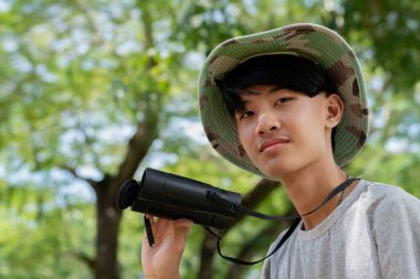 Kamuflaj şapkalı genç bir kaşif dürbününü tutuyor. Doğayı izlerken poz veriyor..