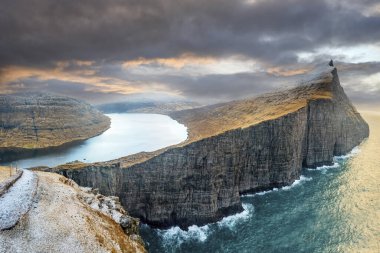  Vagar adasının kayalıklarında, Faroe Adaları 'ndaki bulutlu gökyüzünün altında Sorvagsvatn Gölü