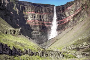 Doğu İzlanda 'da Hengifoss şelalesi. Bazaltik katmanlar arasındaki kırmızı kil katmanları