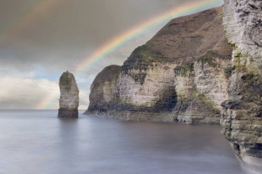 Flamborough yakınlarındaki Thornwick Körfezi 'nin kayalıkları, İngiltere' nin Kuzey Denizi 'nin kuzeydoğu kıyısında, Yorkshire' da, karanlık bir gökkuşağı altında..