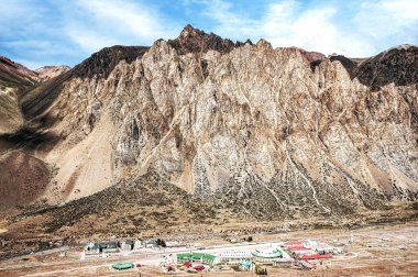 This photo depicts the Los Penitentes ski resort in Chile, nestled at the base of the Andes Mountains. The towering rocky cliffs dominate the arid landscape, offering a spectacular view. The resort buildings contrast with the rugged terrain, creating clipart