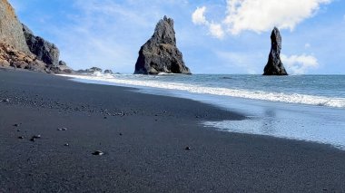 İzlanda, Reynisfjara 'nın kara plajı ve okyanusta Reynisdrangar' ın bazalt yığınları..