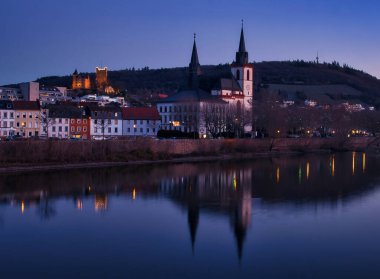 Bingen am Rhein, Almanya - 10 Ocak 2021: St. Martin Kilisesi Bazilikası ve Rhein nehri ve Klopp kalesinin yanındaki diğer binalar, Almanya 'nın Bingen am Rhein kentinde bir kış akşamı arka planda parladı..