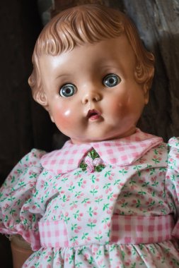 Pembe çiçekli beyaz bir elbise giyen antika bir bebek..