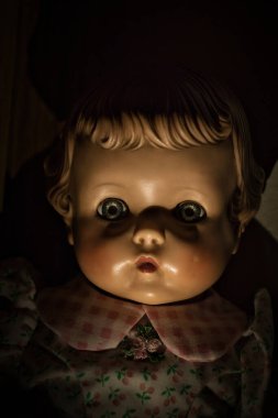 Karanlık odada, yüzünde gölgeler olan ürkütücü bir bebek..
