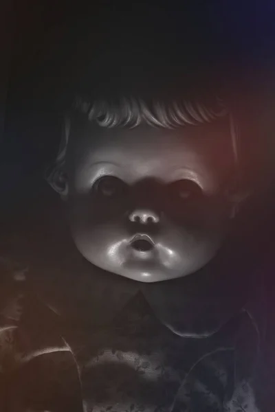 Creepy light and shadows on the face of an antique doll in a dark room.