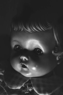 Parlak ışık ve gölgeler karanlık bir odada antik bir bebek yüzünde.