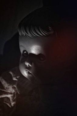 Karanlık bir odada, korkunç bir antika bebeğin üzerine sertçe gölgeler..