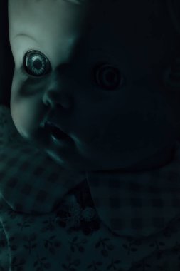 Yüzünde sert bir gölge olan antika bir bebeğe ürkütücü yeşil ışık..