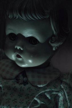 Ürkütücü yeşil ışık ve karanlık bir odada antik bir bebeğin gözleri üzerinde gölgeler..