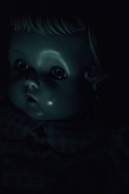 Çok karanlık bir odada antika bir bebeğin yüzüne yeşil ışık..