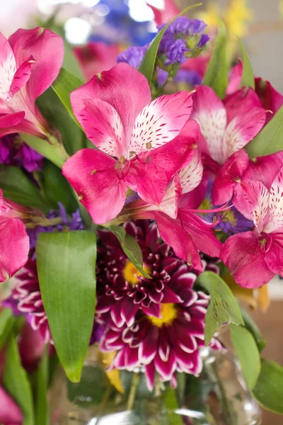 Pink, purple and maroon flowers in a clear vase.