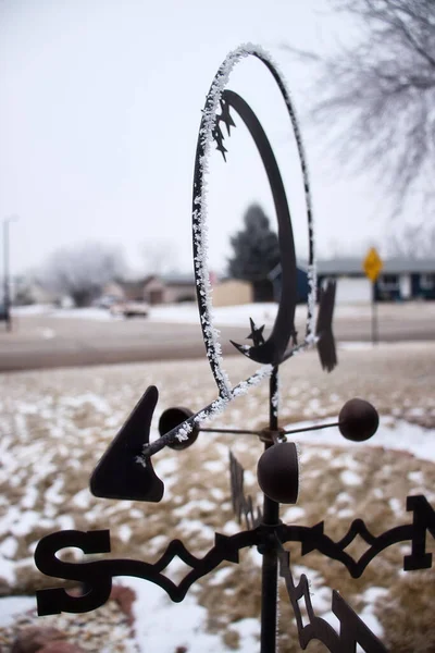 Ice and snow on weather vane in yard in Gillette, Wyoming on a cold cloudy winter day.