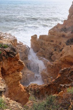 Water running over rocks next to the Atlantic Ocean on a beach in Carvoeiro, Portugal on a warm winter day.