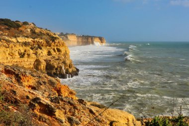 Waves in the Atlantic Ocean heading toward cliffs on a windy winter day in Carvoeiro, Portugal.