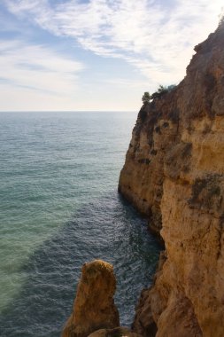 Clouds in a blue sky over a cliff in the Atlantic ocean on a sunny winter day in Portugal.