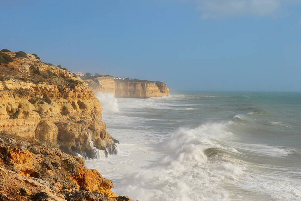Large waves in the Atlantic Ocean and splashing on the cliffs on a warm, windy winter day in southern Portugal.