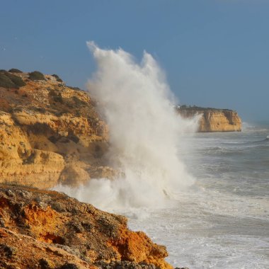 Water splashing over tall cliffs in the Atlantic Ocean near Carvoeiro on a windy winter day in Portugal.