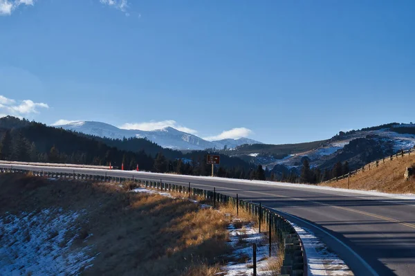 Highway on a sunny winter day with a blue sky over the Bighorn Mountains in Wyoming.
